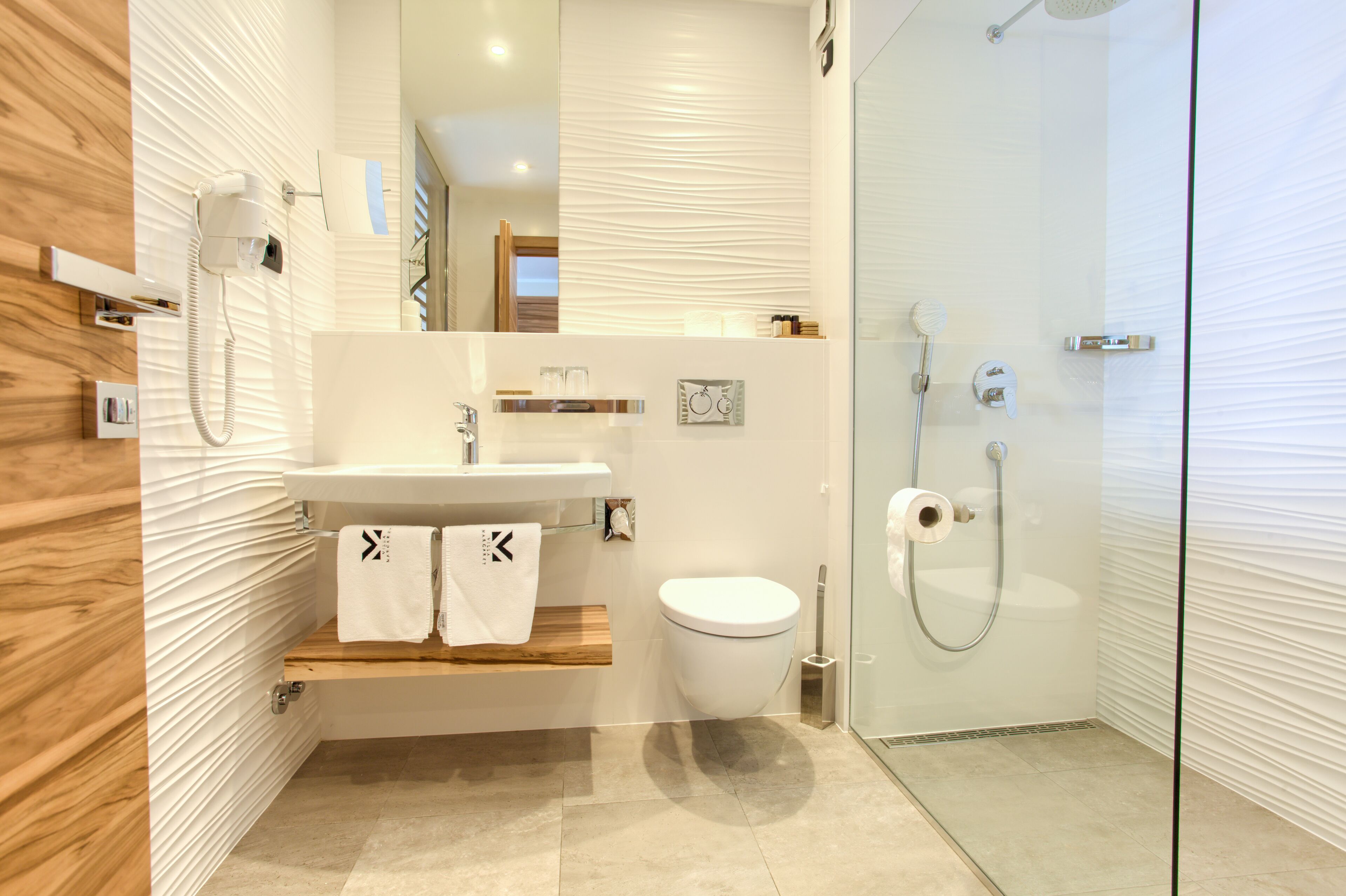A modern bathroom with a wooden vanity, a glass shower enclosure, and a white toilet.