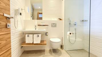 A modern bathroom with a wooden vanity, a glass shower enclosure, and a white toilet.