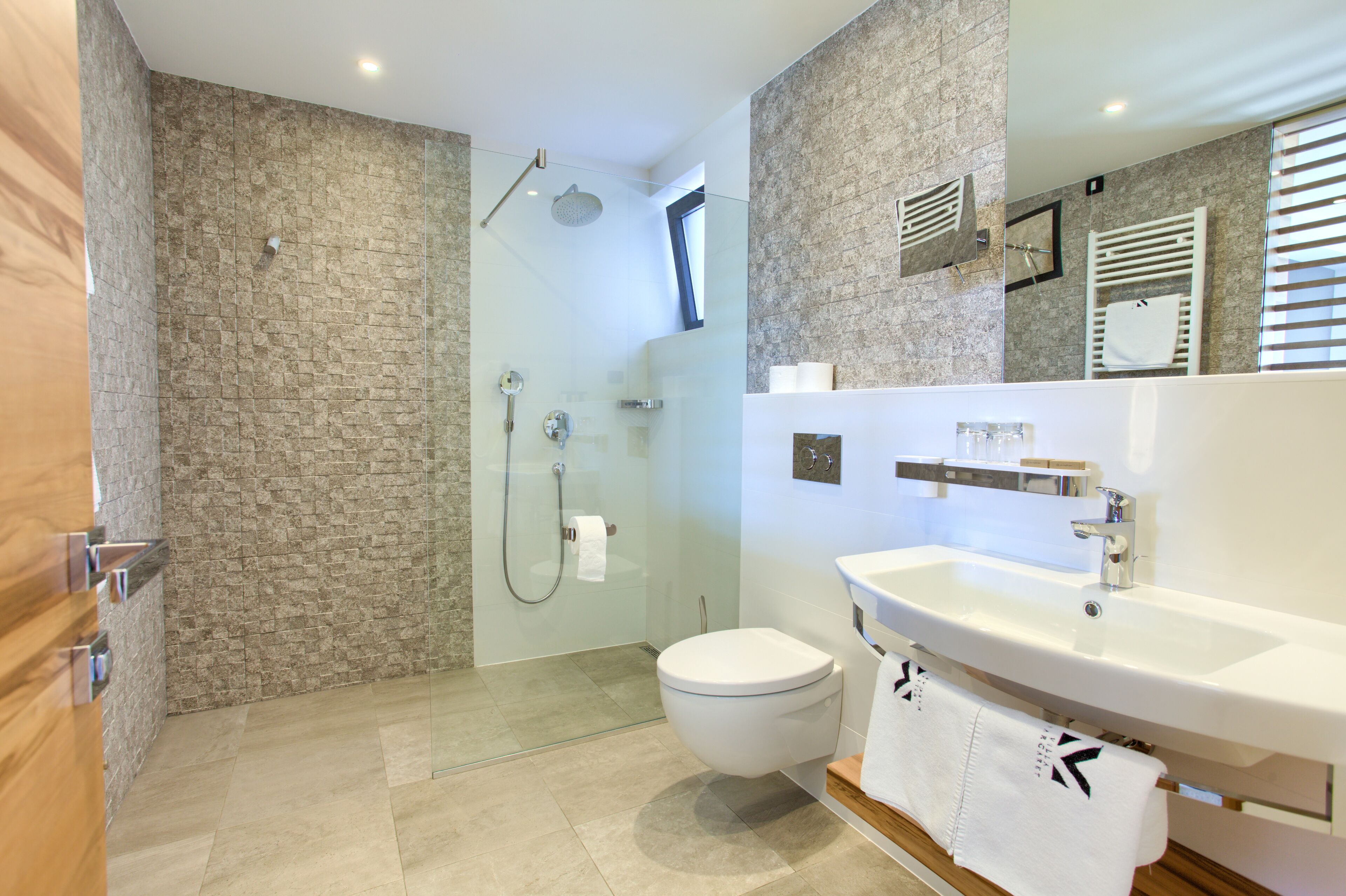 A modern bathroom with a glass-enclosed shower, a white toilet, and a large sink with a mirror above it.