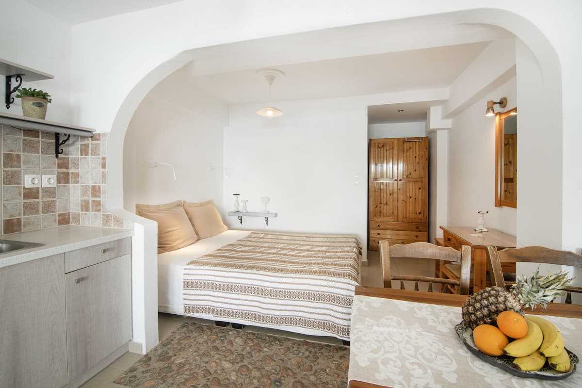 Une chambre avec un lit, un petit bureau et un panier de fruits sur une table de chevet.