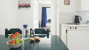 Una cocina con una mesa dispuesta para dos personas, una tetera y un refrigerador.