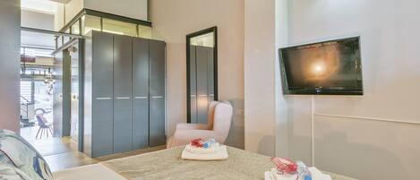 Une chambre d’hôtel avec un lit, un téléviseur fixé au mur, une armoire et une chaise.