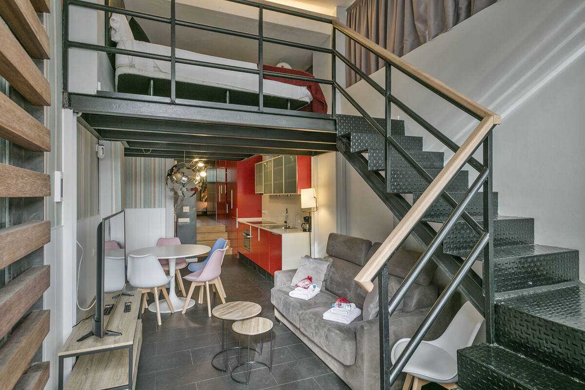 A modern interior with a dining area, a sofa, and a staircase.