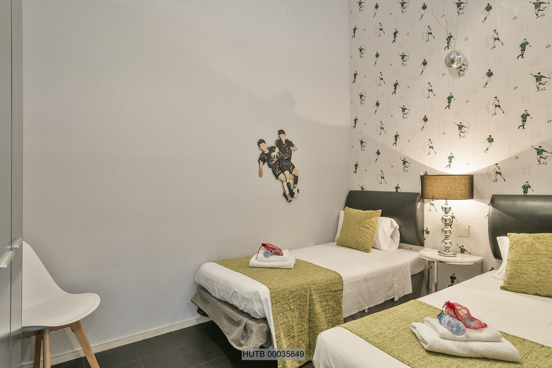 A hotel room with two beds, a nightstand, a lamp, and a wall decoration.