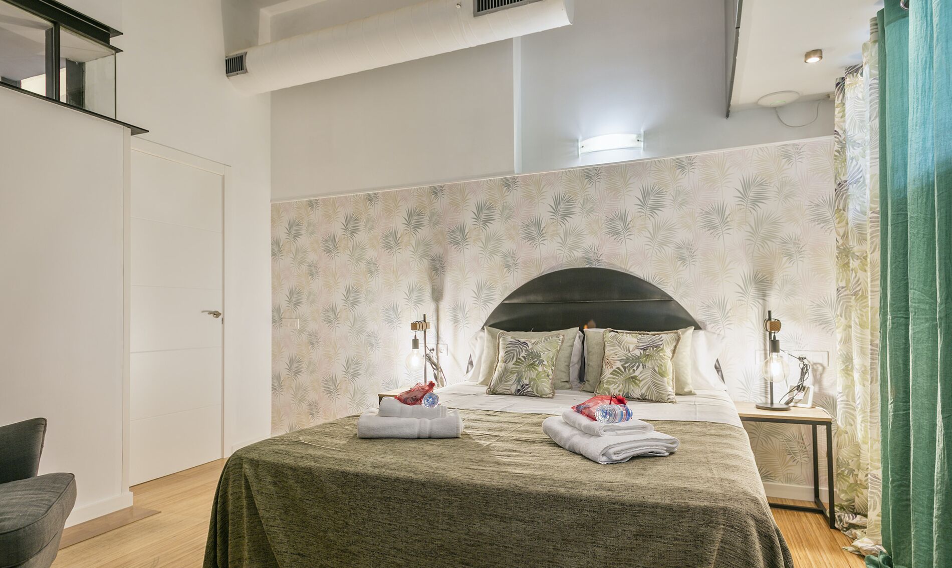A bedroom with a bed, a nightstand, a lamp, and a bathroom with a shower curtain.