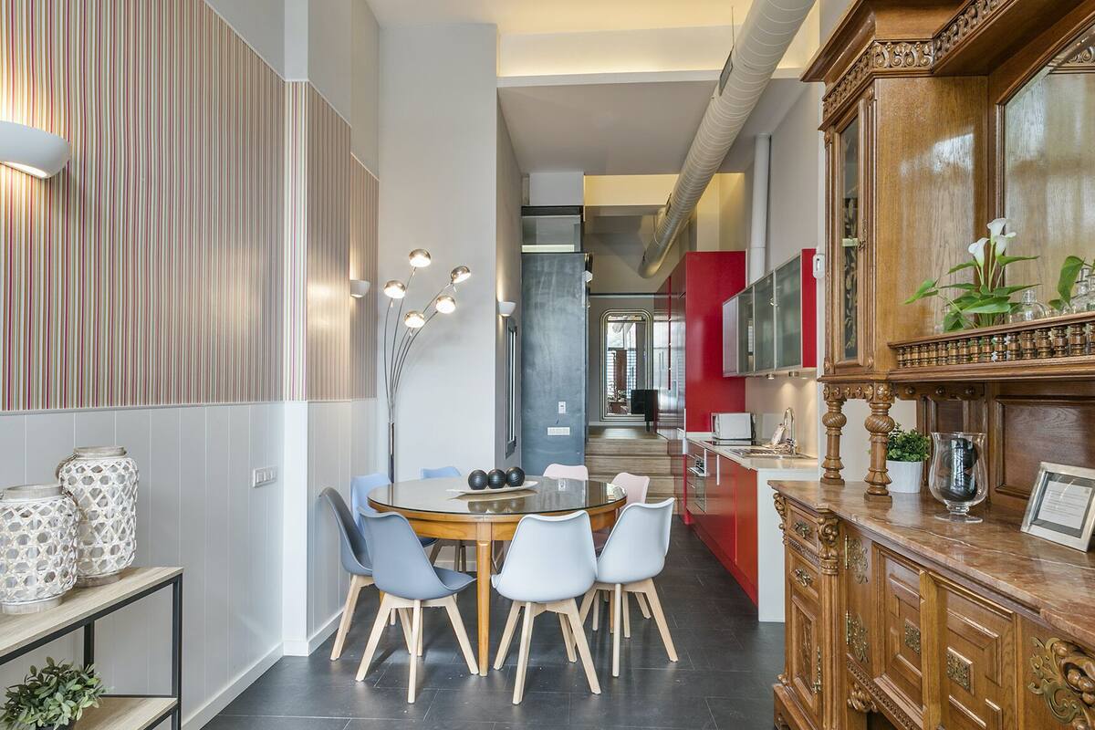 A modern dining area with a round table, six chairs, and a decorative cabinet.