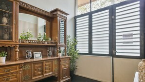 A room with a wooden cabinet, a large mirror, and a window with blinds. - Alcam Futbol (Barcelona)