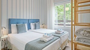 A hotel room with two beds, a wooden bunk bed, a large window with a view of greenery, and a striped wall. - Alcam Futbol (Barcelona)