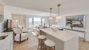 A modern hotel room with a large balcony, a dining area, and a bed with a view.