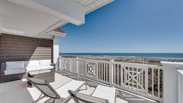 Enjoy the ocean view from this balcony with a sofa, chairs, and table.