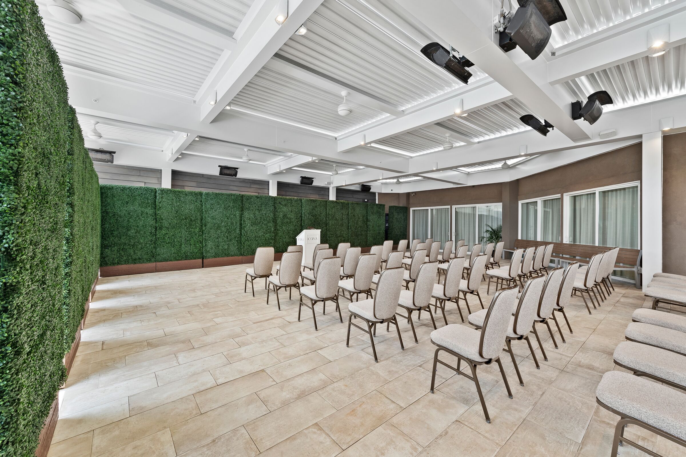 Un salón de conferencias con filas de sillas, una pared verde y un techo alto con luminarias.
