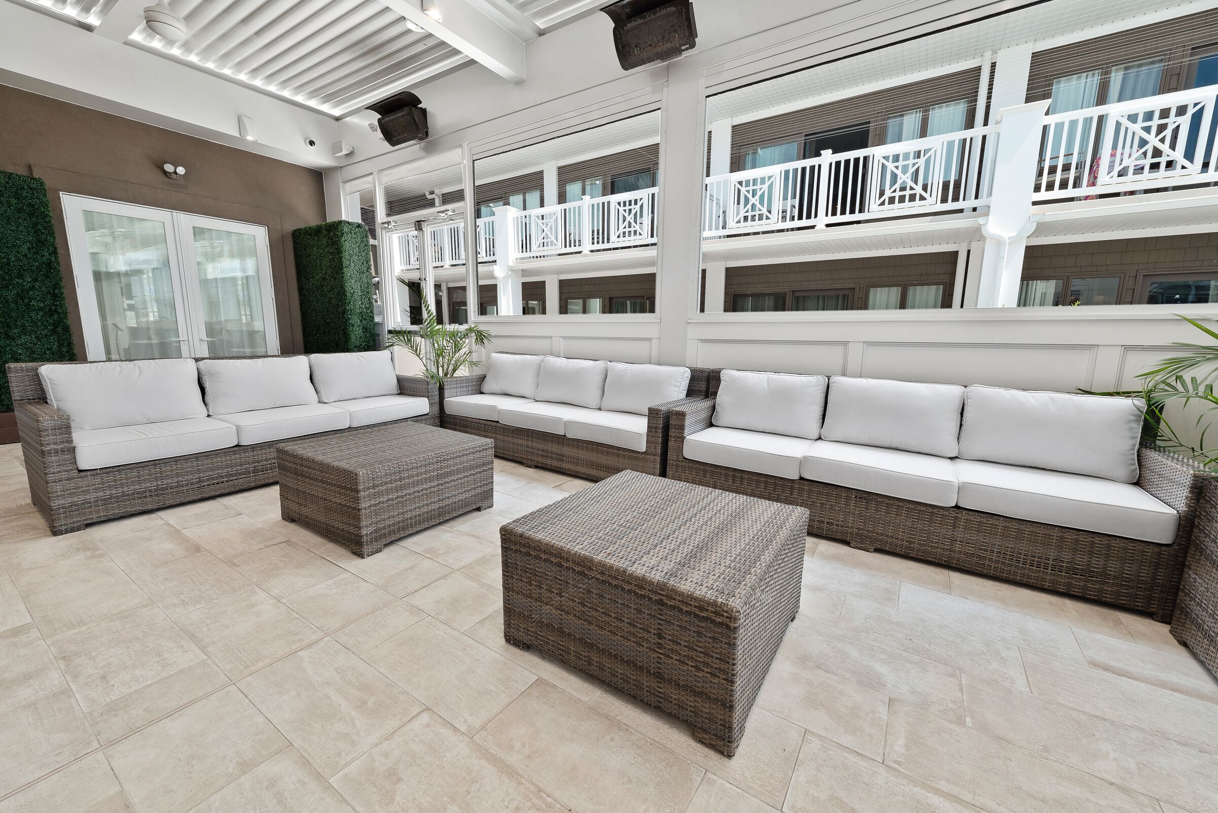 A spacious indoor lounge with wicker furniture, a high ceiling, and a view of the building's exterior balconies.