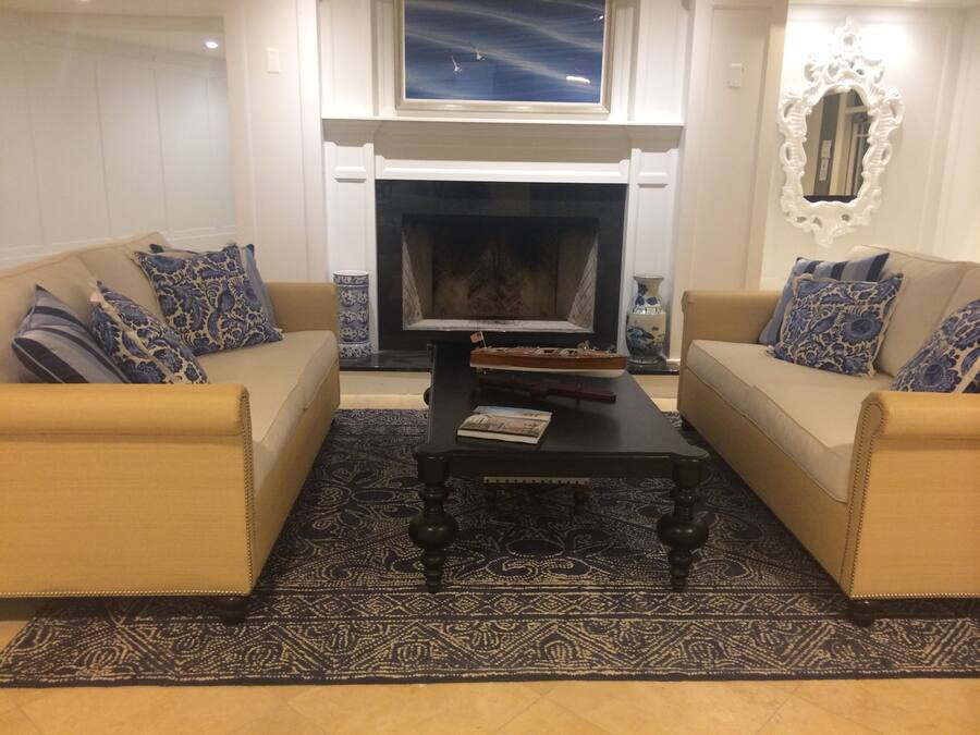 A living room with two beige sofas, a dark coffee table, and a patterned rug.