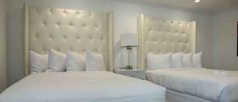 A hotel room with two beds, each with a tufted headboard and white bedding.