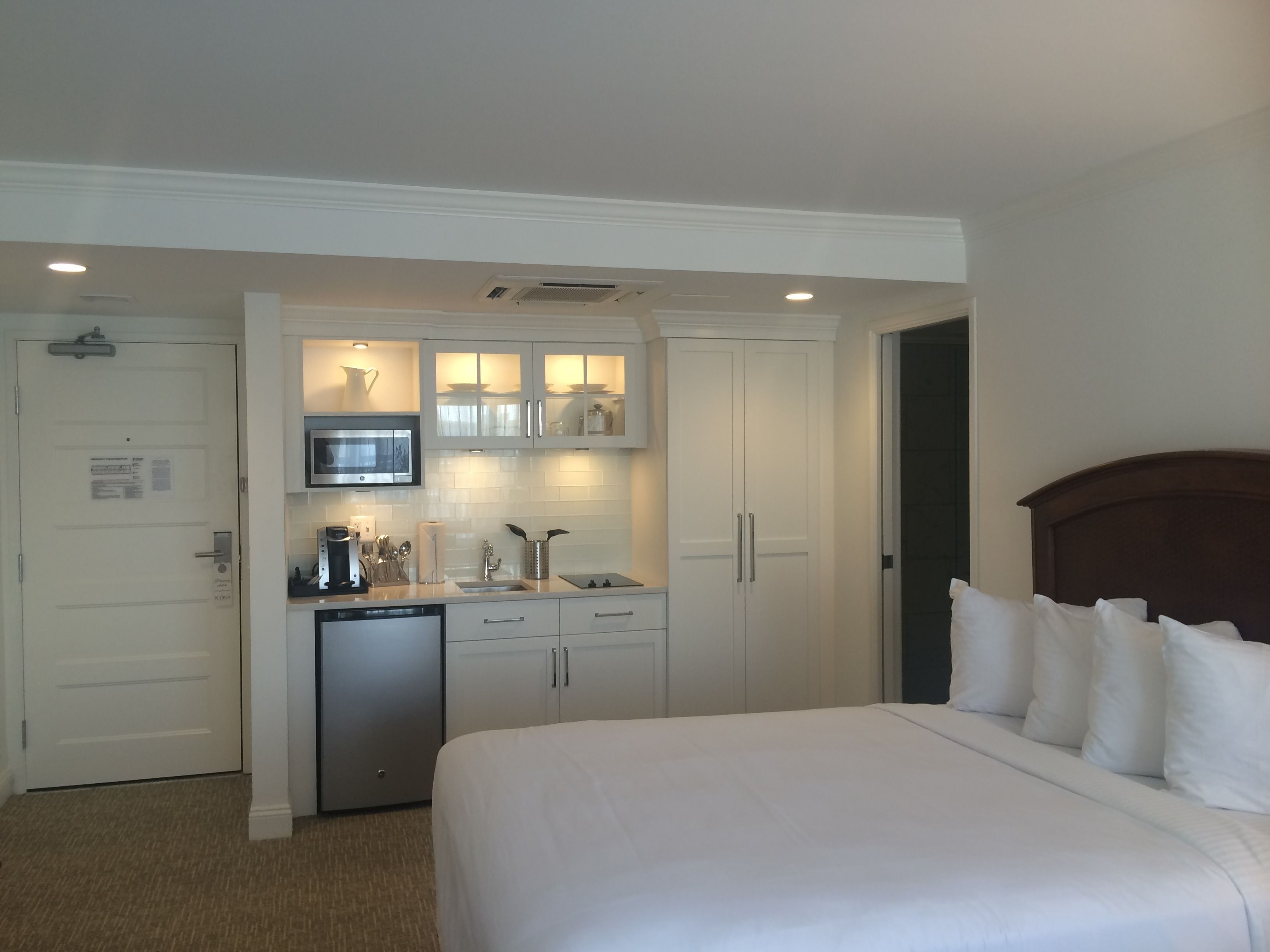 A hotel room with a bed, a small kitchenette, and a separate bathroom.