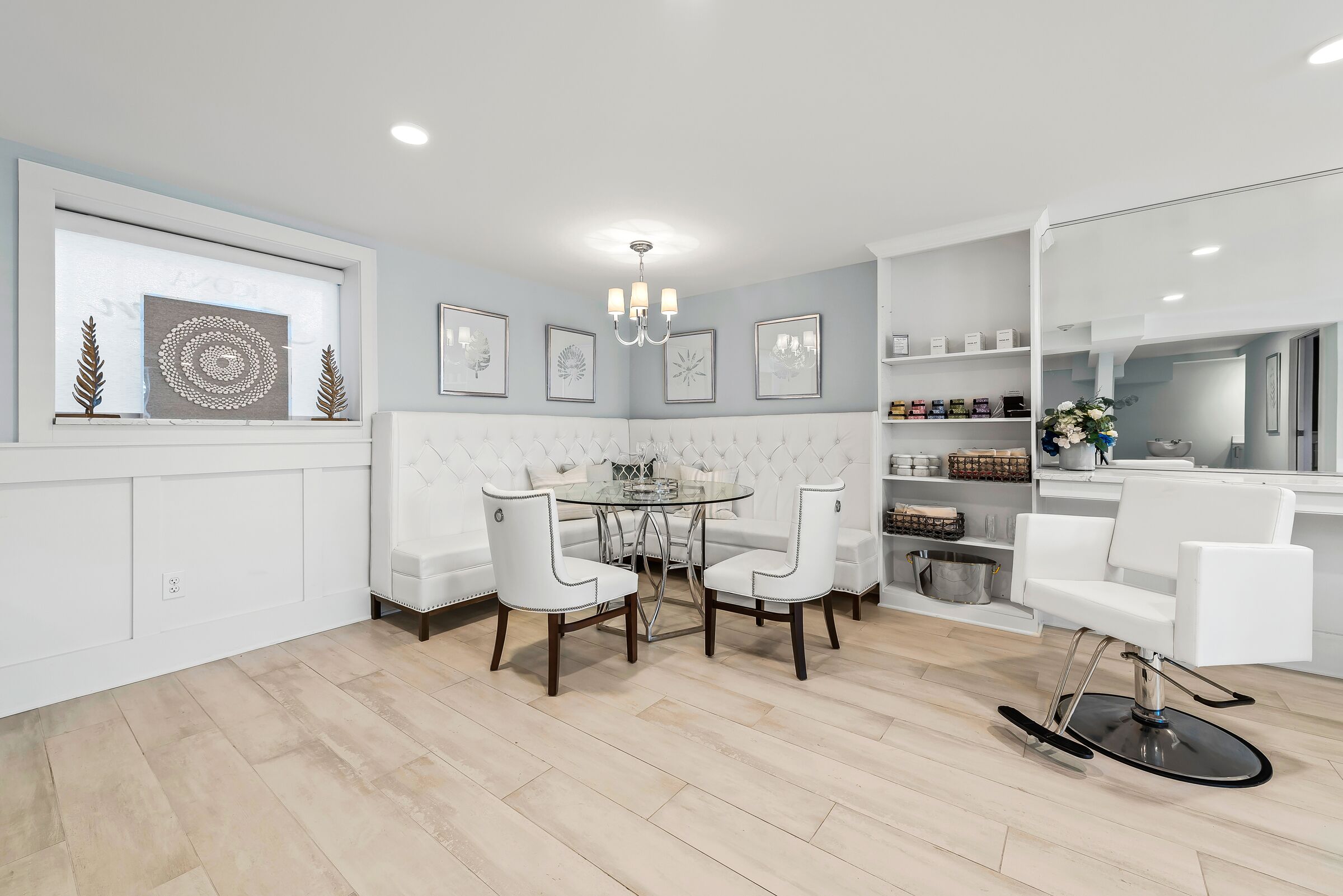 A modern kitchen with a dining area, white cabinetry, a round table, and a built-in bench.