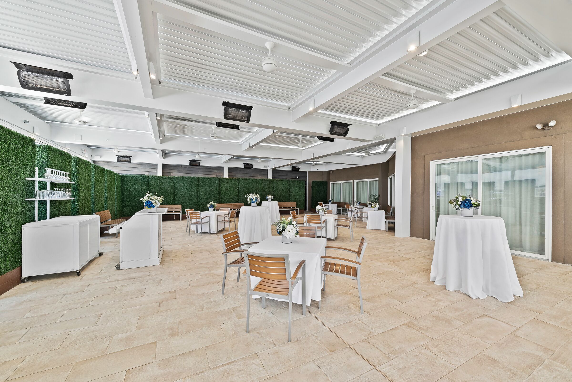 Un espace intérieur spacieux avec des tables et des chaises blanches, un mur vert et une grande fenêtre.