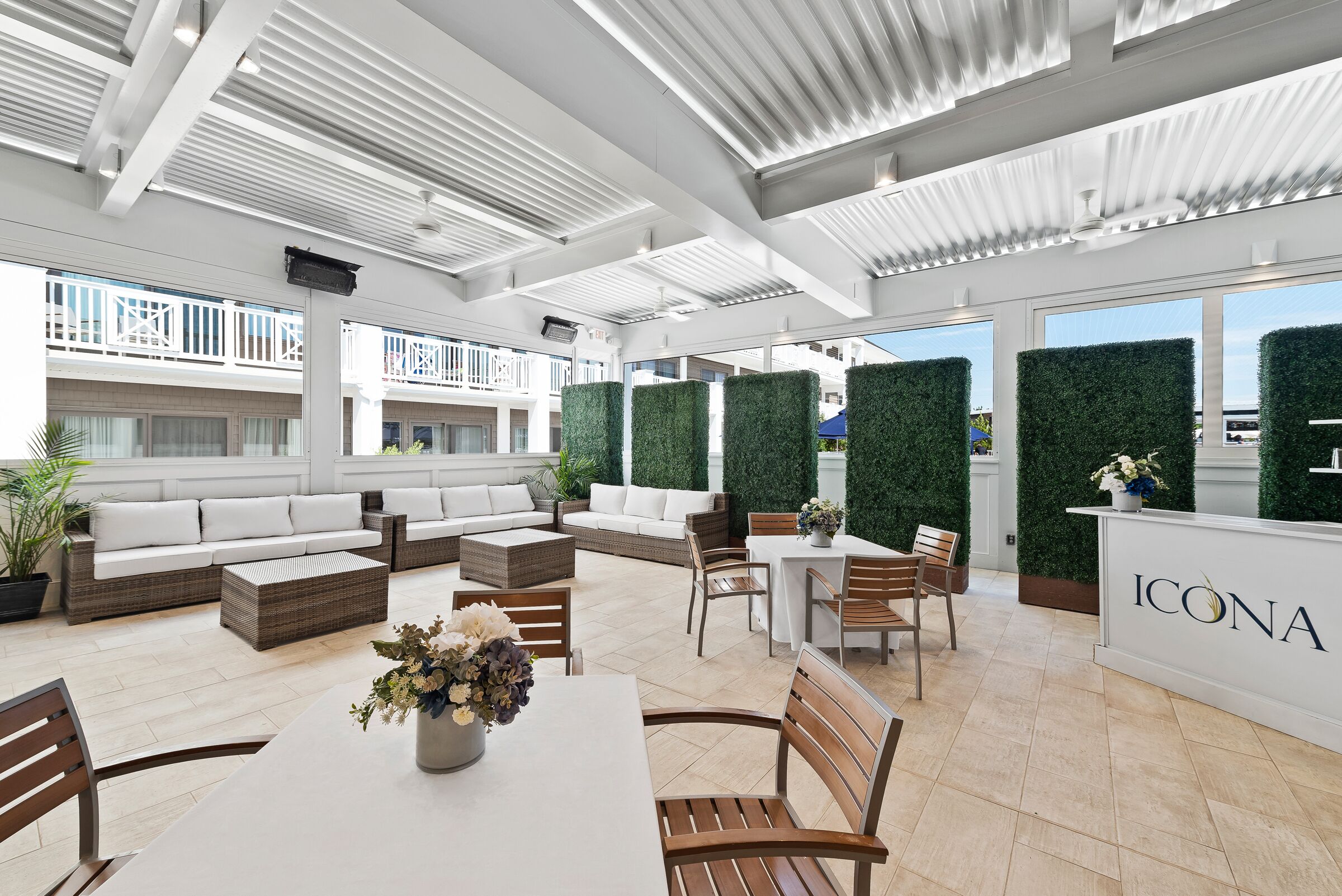 A modern outdoor lounge area with seating arrangements, a reception desk, and a view of the cityscape.