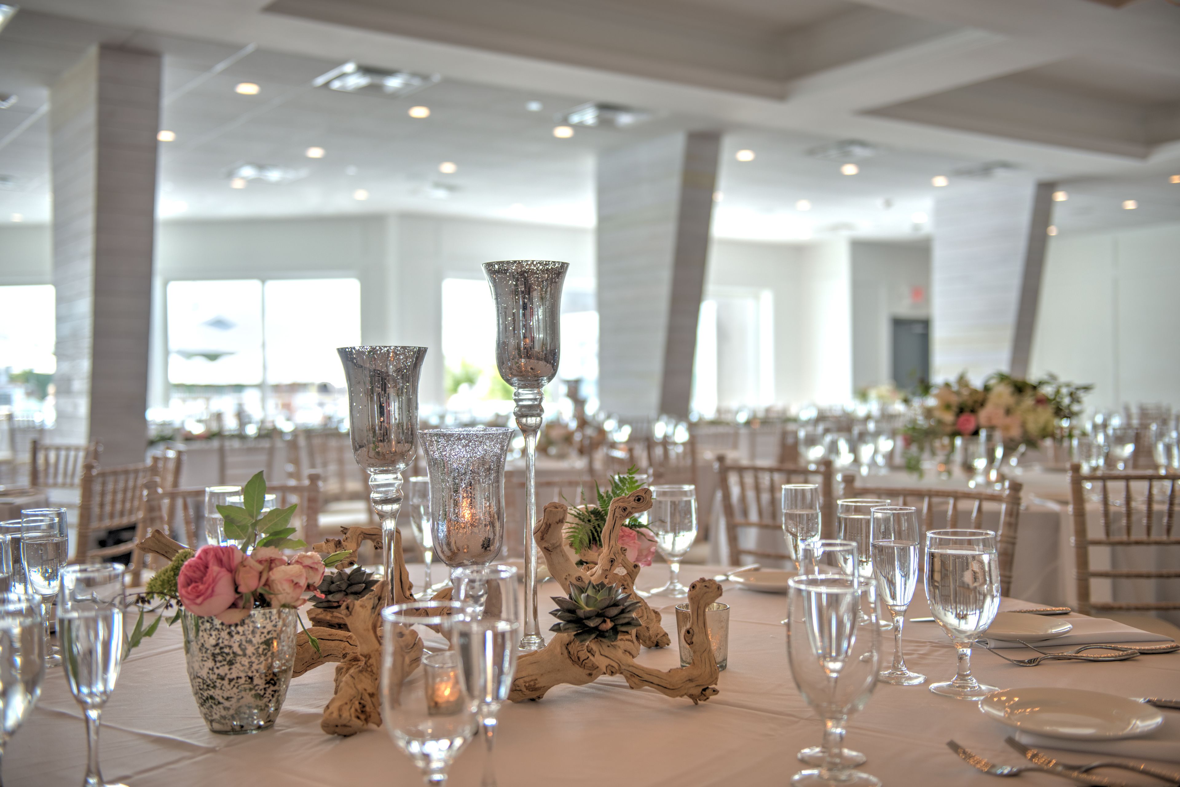 A banquet hall with tables set for a formal event, featuring floral centerpieces and elegant tableware.