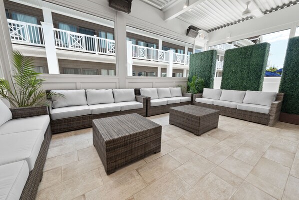 A spacious outdoor seating area with wicker furniture and a view of the building's balconies. - ICONA Avalon (Avalon)