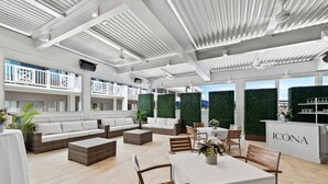 A spacious indoor area with a high ceiling, white railings, and a dining area with a table set for two.