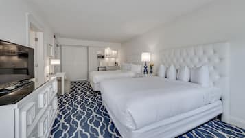 A hotel room with a large bed, a desk with a TV, a kitchenette, and a bathroom.