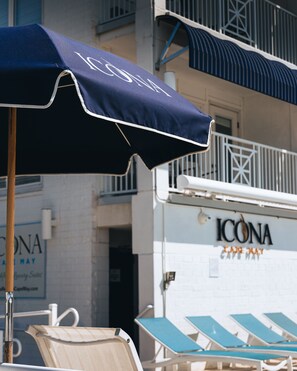 Una sombrilla de playa, sillas de descanso y un edificio con letrero "ICONA".