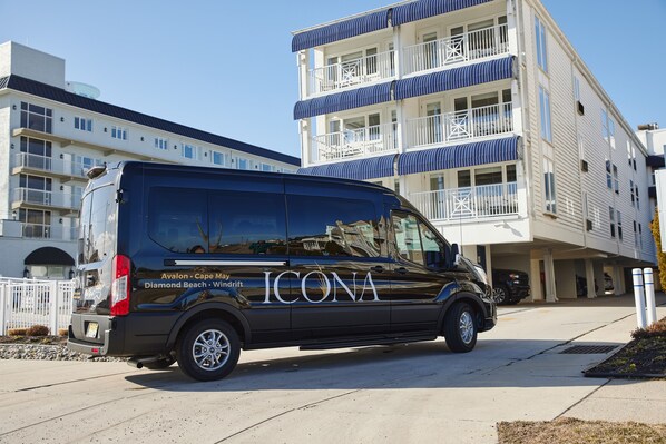 Una camioneta ICONA negra estacionada frente a un edificio de varios pisos con balcones y un cielo despejado.