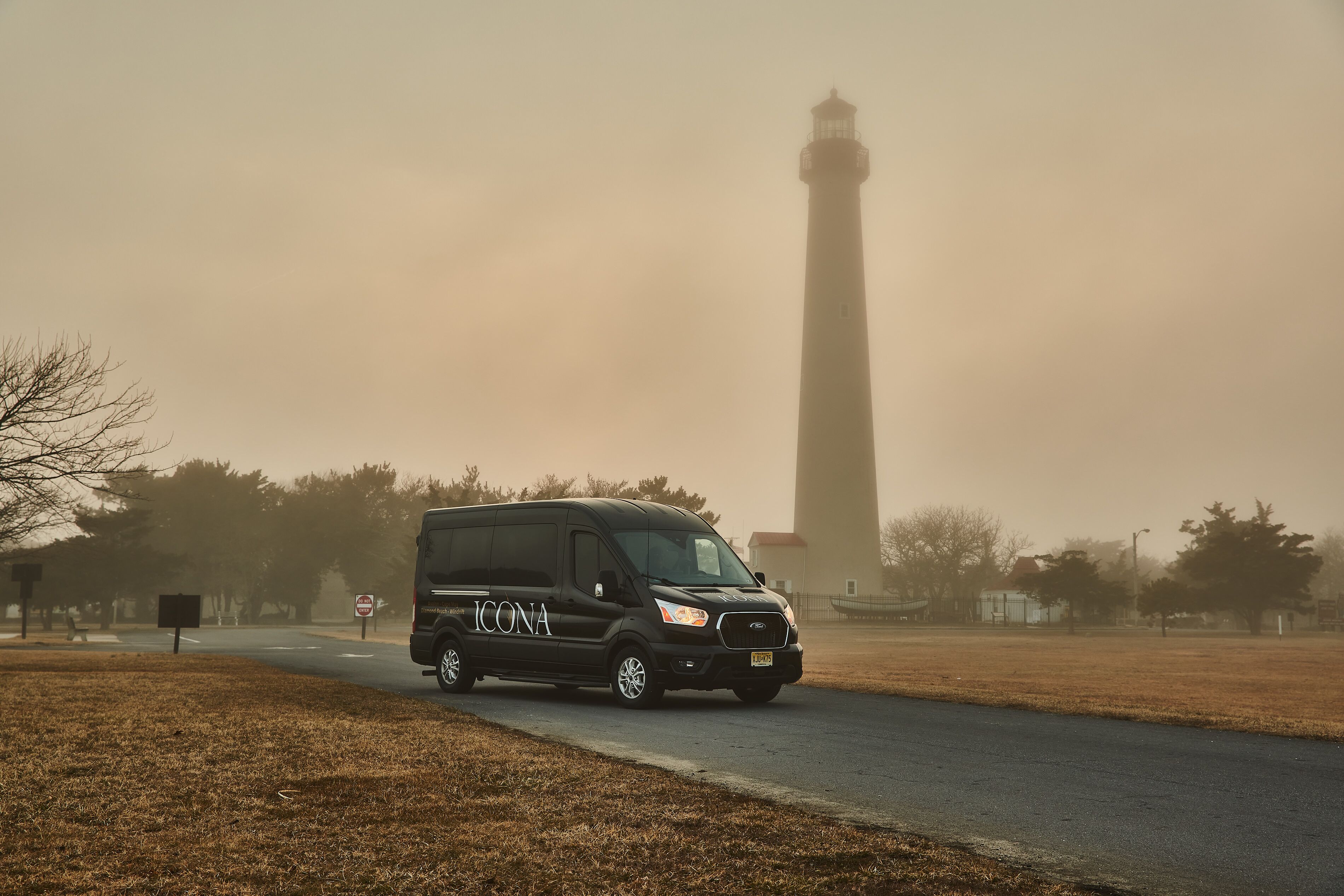 Una camioneta ICONA negra estacionada en una carretera con un fondo brumoso y una torre alta.