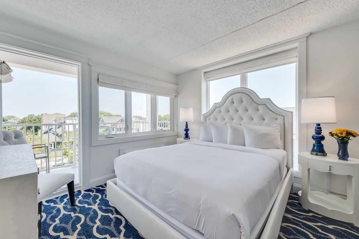 A hotel room with a large bed, a desk, and a view of the city.