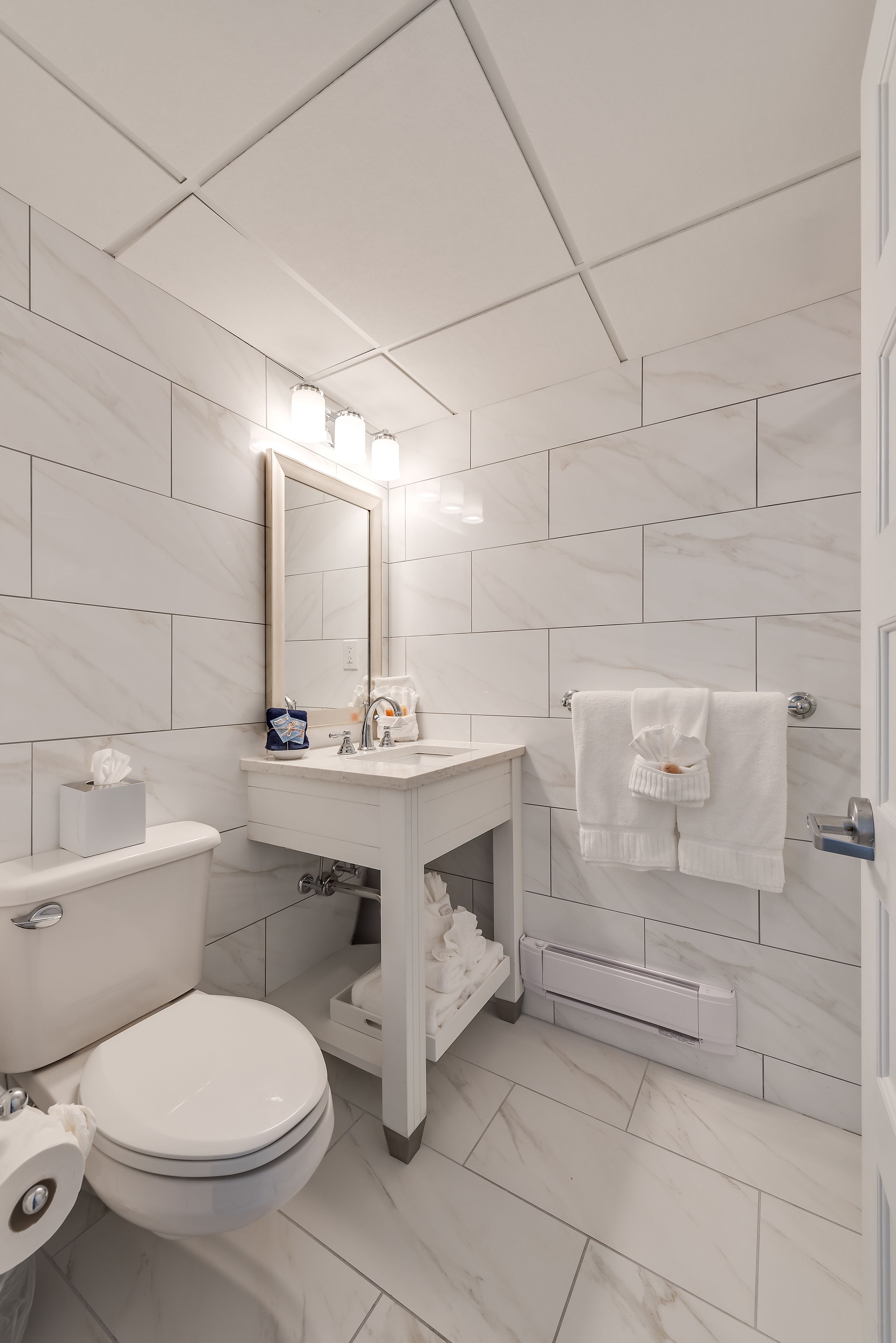Ein modernes Badezimmer mit Toilette, Waschbecken und Spiegel, alles in Weiß.