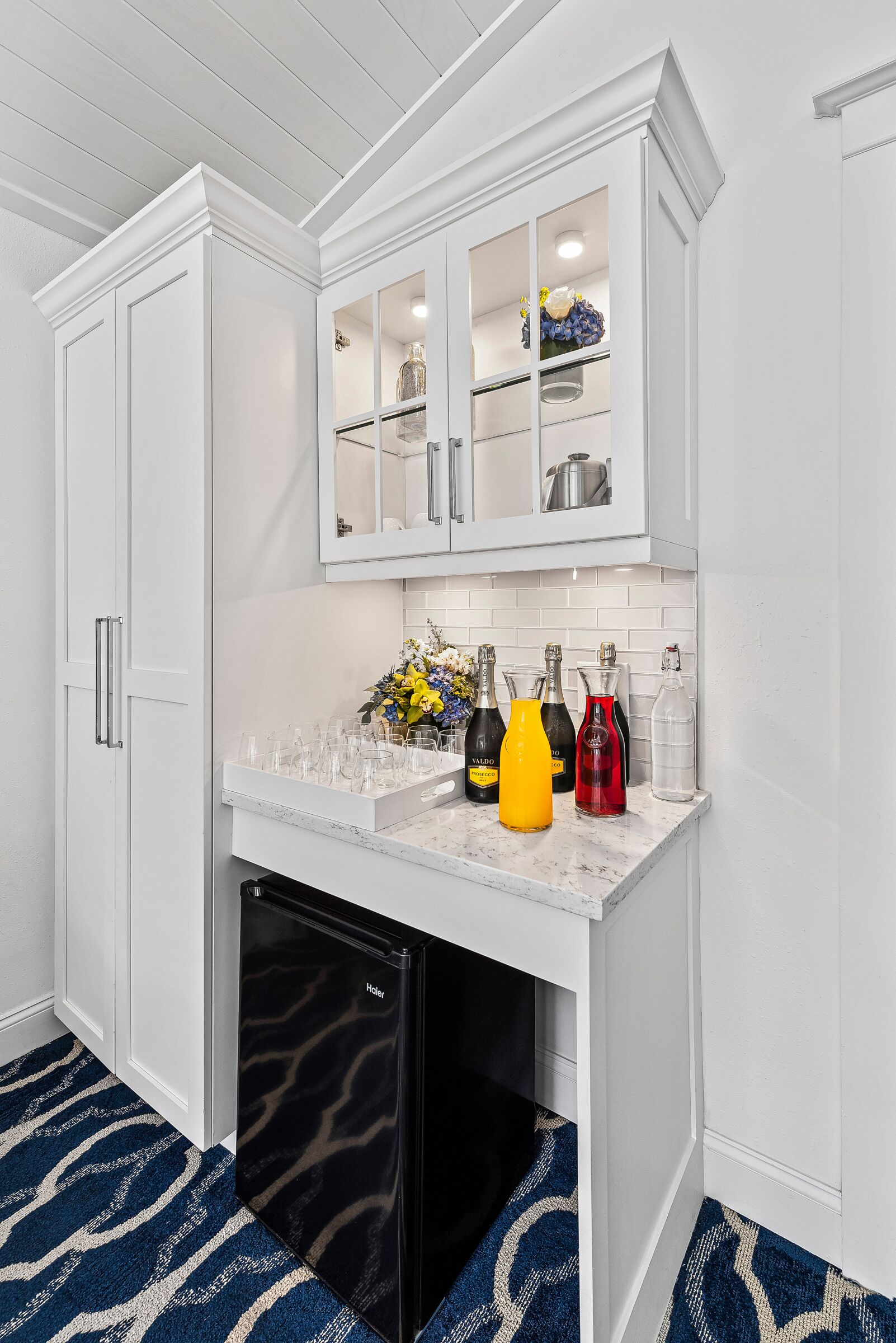 A compact kitchen with white cabinetry, a built-in refrigerator, and a countertop with various items.