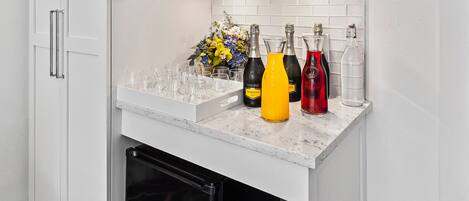 A compact kitchen with white cabinetry, a built-in refrigerator, and a countertop with various items.