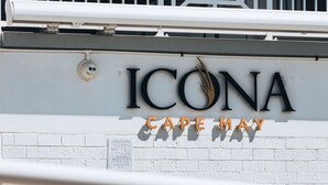 Letrero de ICONA Cape May, con un fondo de pared de ladrillo blanco y una zona de piscina visible abajo.