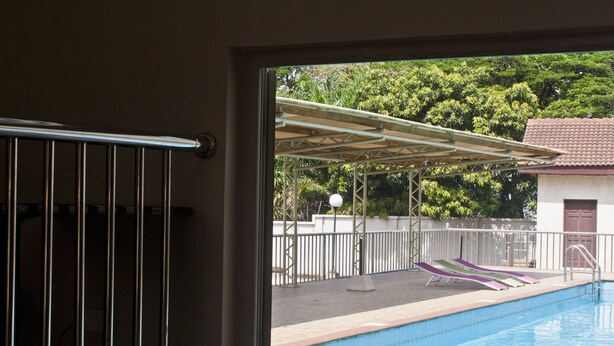 Une piscine dotée d’un espace couvert et de chaises longues.