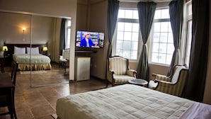 Une chambre d’hôtel avec un lit, une télévision, un bureau, une chaise et une fenêtre avec des rideaux.