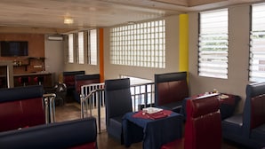 Un restaurant avec des banquettes et des tables, un mur en briques et un téléviseur.