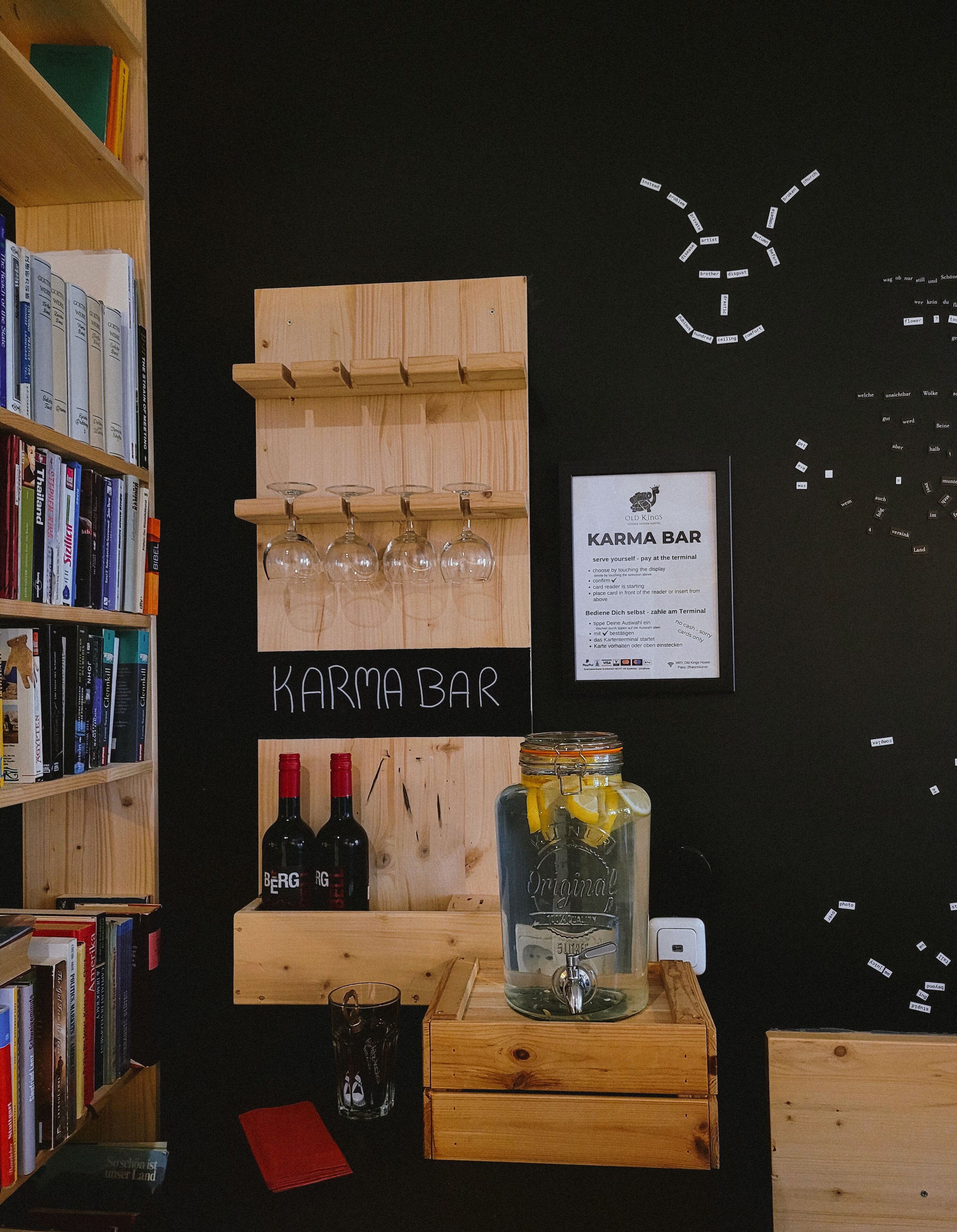 A bar area with wooden shelves holding wine bottles and glasses, a sign reading "Karma Bar", and a menu board.