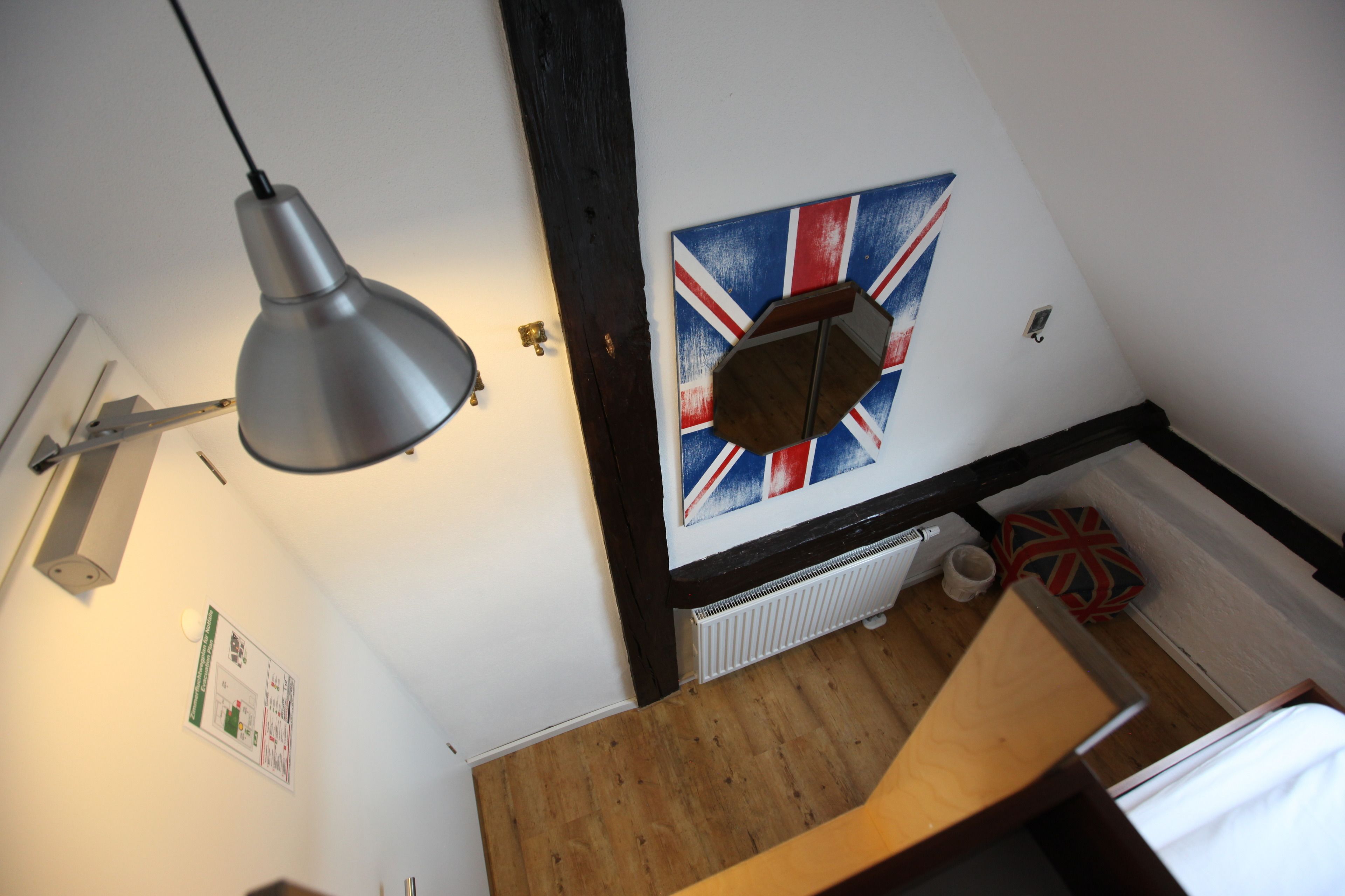 Una habitación con un escritorio de madera, una lámpara de pared, una bandera del Reino Unido y un radiador.