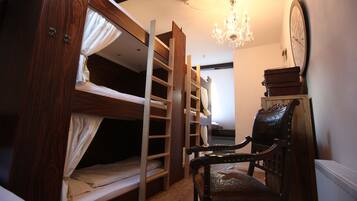 Quarto com beliche, uma cadeira de madeira e um relógio na parede.