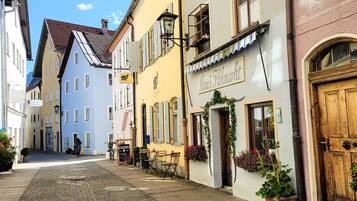 A cobblestone street lined with colorful buildings, including a restaurant named "Nina's Floremarkt" with outdoor seating.
