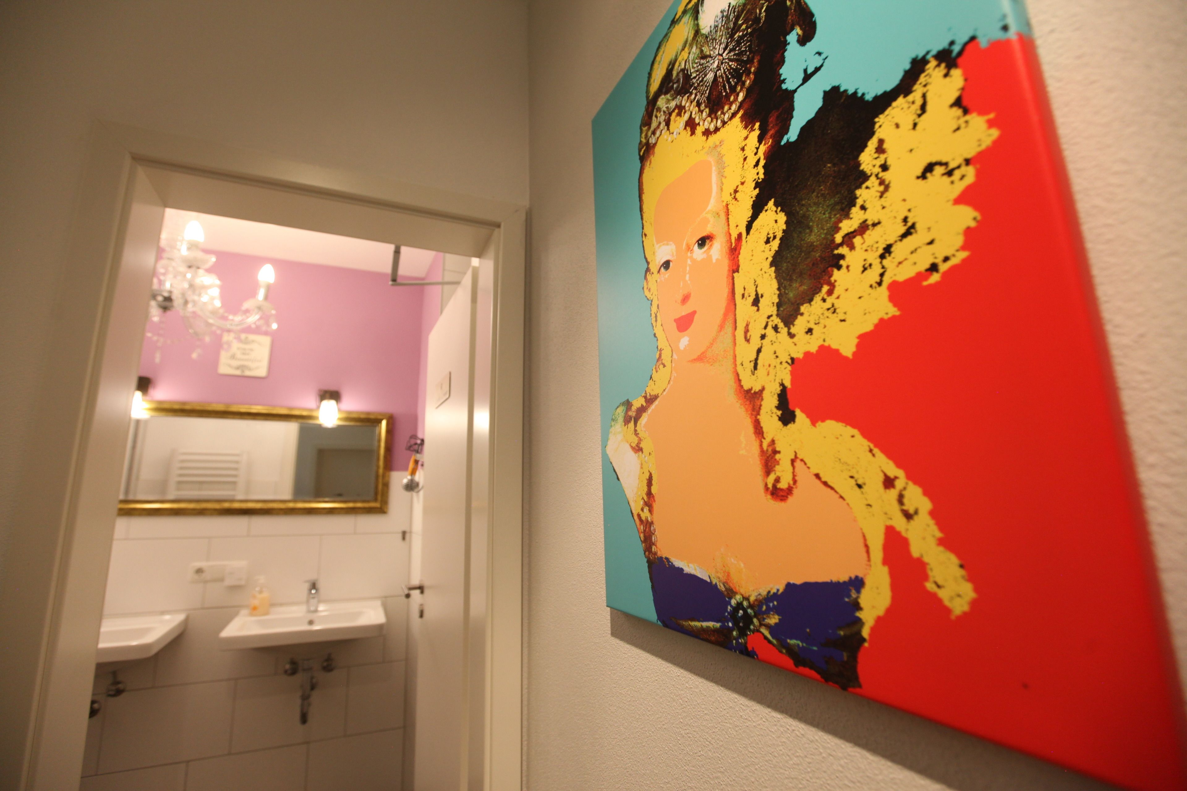 A bathroom with two sinks, a mirror, and a colorful painting on the wall.