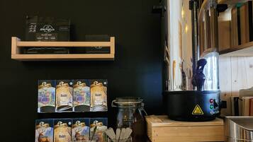 Una encimera de cocina con una cafetera, un tarro de azúcar y sobres de café.