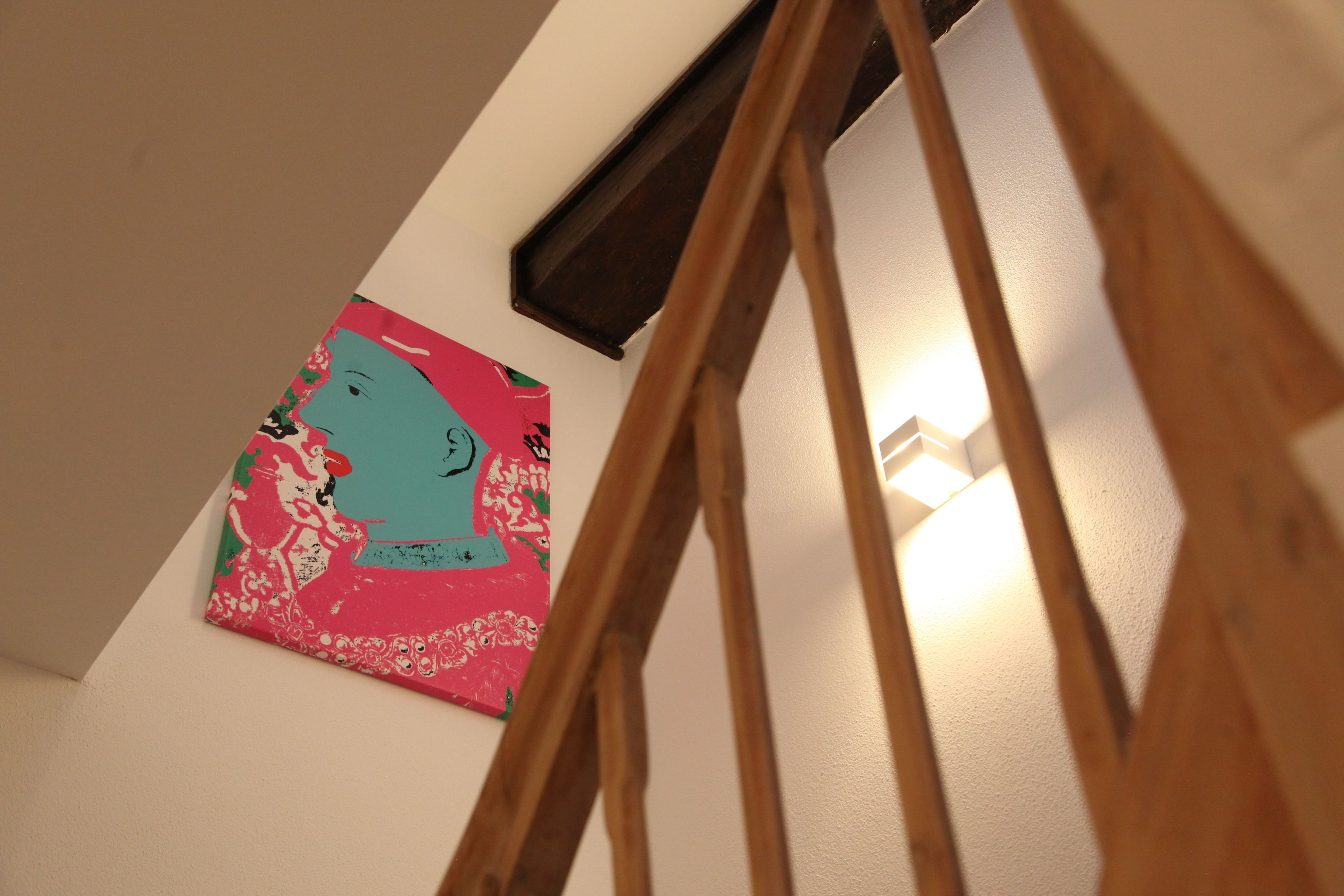 A staircase with wooden handrails and a wall-mounted artwork featuring abstract figures.