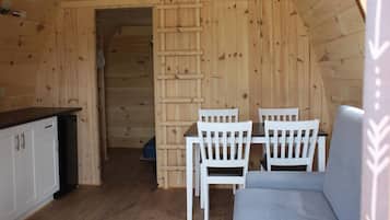 A wooden interior with a kitchen area, dining table, and chairs.