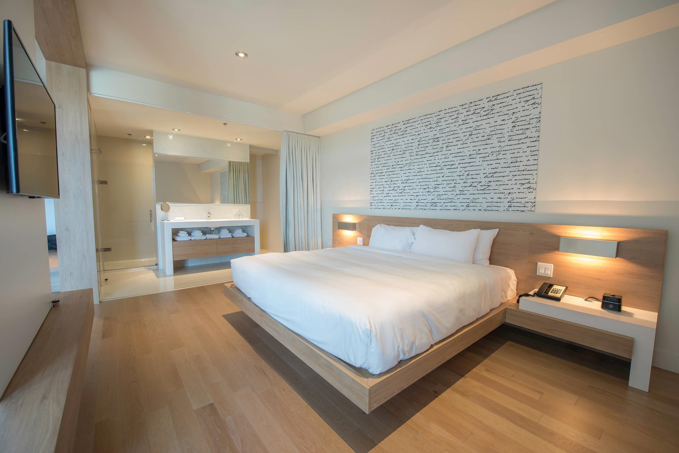 Un dormitorio moderno con una cama grande, mesitas de noche, un armario empotrado y una obra de arte colgada en la pared.