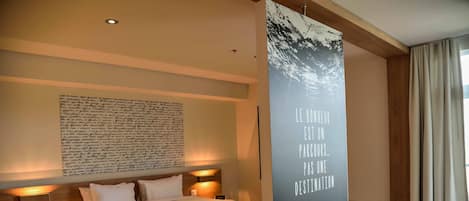 Un dormitorio moderno con una cama grande, mesitas de noche, una obra de arte colgada en la pared y un equipo de aire acondicionado integrado.