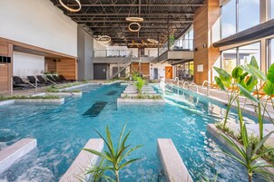 Piscina interna com design moderno, cercada por espreguiçadeiras e plantas.
