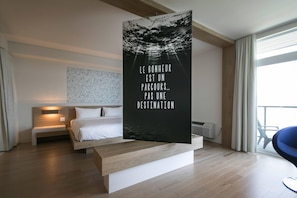 Une chambre d’hôtel moderne, équipée d’un lit, d’une table de chevet et d’une grande fenêtre.