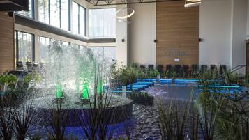A spacious indoor area with a water feature in the center, surrounded by seating and plants.